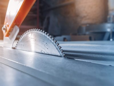 Closeup of wood cutting table with electric circular saw. Professional carpenter cutting wooden board at sawmill
